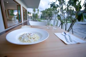 a white plate of pasta on a wooden table at West View Villa in Kanchanaburi