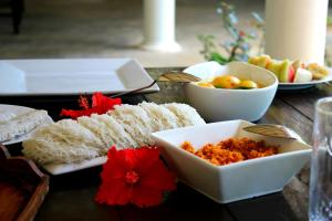 a table topped with plates of food and bowls of fruit at The Courtyard Villa in Sigiriya