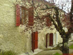 SosにあるLe Petite Grange Giteの赤い扉と木の前の建物