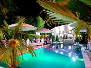 a swimming pool with palm trees and umbrellas at Hotel Elisabeta in Alba Iulia