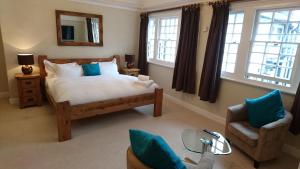 a bedroom with a bed and a chair and windows at The Angel Posting House & Livery in Guildford