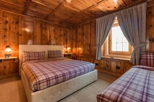a bedroom with two beds in a room with wooden walls at Bait da Menego in Livigno