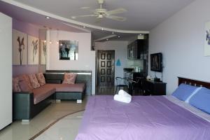 a bedroom with a purple bed and a couch at Viewtalay Beachfront by ND in Pattaya South