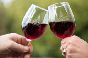 twee mensen die een glas rode wijn omhoog houden bij Church Hill Boutique Lodge & Restaurant in Half-moon Bay