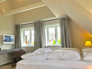 a bedroom with two beds and a desk and windows at Kleiner Ulenhof in Wenningstedt