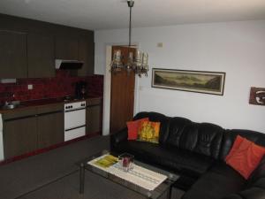 a living room with a black couch and a kitchen at Ferienwohnung Frei in Bad Ragaz