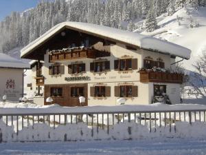 um edifício coberto de neve com uma cerca em frente em Pension Hartenfels em Lech am Arlberg