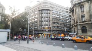 eine belebte Stadtstraße mit Spaziergängern und einem gelben Taxi in der Unterkunft Studio Central Exer II in Bukarest