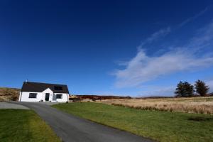 a white house on the side of a road at Hillside in Dunvegan