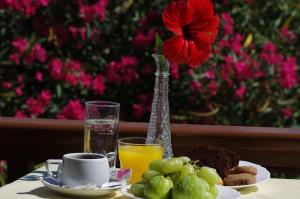 a table with a plate of food and a vase with a flower at Effie Hotel in Skala
