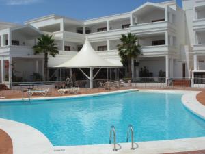 a swimming pool in front of a large building at Apartamentos Oceano - Adults Only - Sólo Adultos in Costa Teguise
