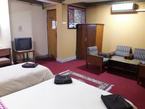 um quarto com duas camas e uma televisão e cadeiras em Hotel Metropolitan Kantipur em Kathmandu