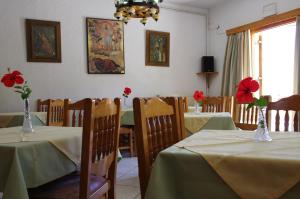 a dining room with two tables with red flowers in vases at Effie Hotel in Skala
