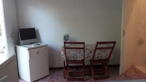 a kitchen with two chairs and a table and a television at Hofste appartementen in Paramaribo