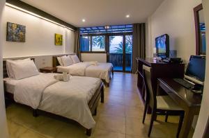 a hotel room with two beds and a desk and a television at Baantalay Thungwualaen in Pathiu