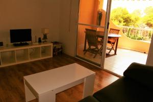 a living room with a couch and a table and a television at Coveta Beach Apartament in El Campello