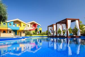 a pool at a resort with a bridge and houses at Alexandra Golden Boutique Hotel-Adults Only in Chrysi Ammoudia