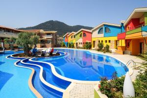 a swimming pool in a resort with colorful houses at Alexandra Golden Boutique Hotel-Adults Only in Chrysi Ammoudia