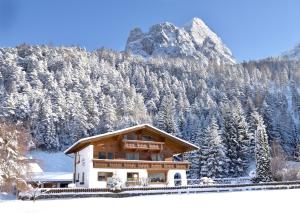 une maison dans la neige avec une montagne en arrière-plan dans l'établissement Landhaus Schmitte, à Biberwier