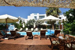 a patio with chairs and tables and umbrellas next to a pool at Villa Katerina in Parikia