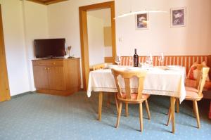een eetkamer met een tafel en een televisie bij Landhaus Schmitte in Biberwier