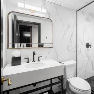een witte badkamer met een wastafel en een spiegel bij The Broadview Hotel in Toronto