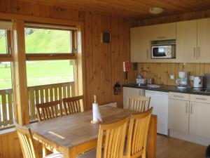 Il comprend une cuisine et une salle à manger avec une table et des chaises en bois. dans l'établissement Vestri Pétursey, à Vestri Pétursey