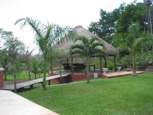 a pavilion with a table and palm trees in a park at Hacienda San Jose Poniente in Hoctún