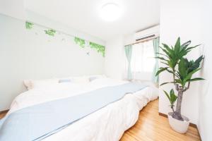 a bedroom with a white bed and a potted plant at Awaji Central Room NC03 in Awaji