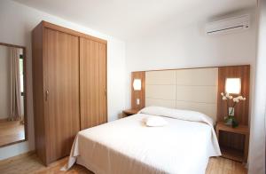 - une chambre avec un lit blanc et une armoire en bois dans l'établissement En Aparté, à Porto-Vecchio