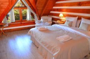 a bedroom with a large white bed and two chairs at Casa del Lago Villa La Angostura in Villa La Angostura