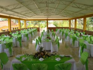 un gran salón de banquetes con mesas blancas y sillas verdes en Bed and Breakfast Campestre El Estoril, en Fusagasuga