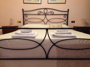 Una cama con marco negro y toallas. en Bed and Breakfast Il Cappero en Rapolano Terme