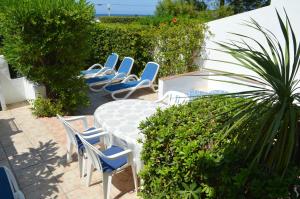 a patio with blue chairs and a table and some bushes at Urbanisation Les Basetes in Denia