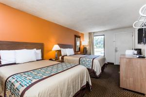 two beds in a hotel room with orange walls at Days Inn by Wyndham Norfolk Airport in Norfolk +40 photos