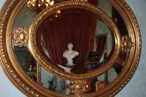 an ornate gold mirror with a man in the reflection at Hotel Giulietta e Romeo in Casal Palocco