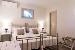 a bedroom with a bed with white sheets and a window at Portes Houses in Koufonisia
