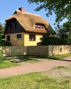 a house with a thatched roof and a fence at Landhaus Selma in Wieck