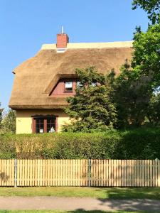 a yellow house with a thatched roof behind a fence at Landhaus Selma in Wieck