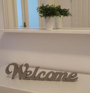 a sign that says welcome on a shelf with a plant at Kurzzeit-Apartment Nussdorf in Vienna