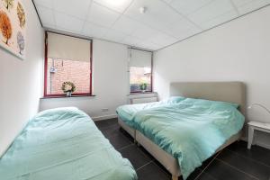1 dormitorio con 2 camas y 2 ventanas en Vakantieappartementen centrum Oudewater, en Oudewater
