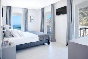a white bedroom with a bed and a balcony at Hotel Mar Bravo in Nazaré