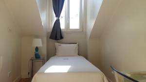 uma cama num pequeno quarto com uma janela em Sincerely Lisboa em Lisboa