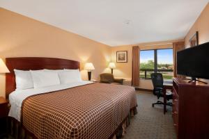 een hotelkamer met een bed en een flatscreen-tv bij Days Inn by Wyndham Utica in Utica