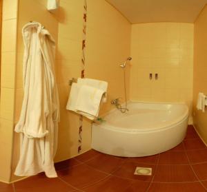y baño con bañera, ducha y toallas. en Tsentralniy Hotel, en Khmelʼnytsʼkyy