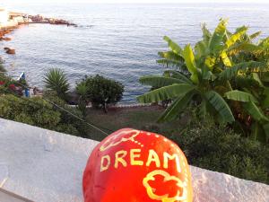 un panneau rouge avec un rêve écrit à côté de l'océan dans l'établissement Alkioni Studios, à Karlovasi