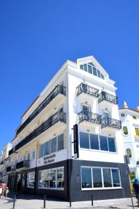 a white building with balconies on the side of it at Hotel Mar Bravo in Nazaré