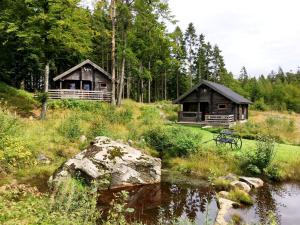 zwei Blockhütten im Wald neben einem Fluss in der Unterkunft Stugby Ullared Paradise in Ullared
