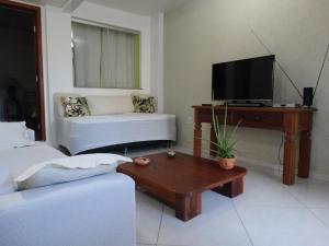 a living room with a tv and a couch and a coffee table at Casa Pontal Ilheus in Ilhéus