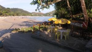 a table and chairs on a beach with a dog at Pousada Seachegue in Ubatuba